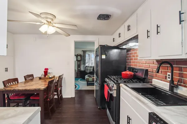 a kitchen with stainless steel appliances a sink dishwasher and a dining table with wooden floor