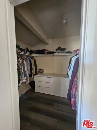a view of walk in closet with clothes and shoes