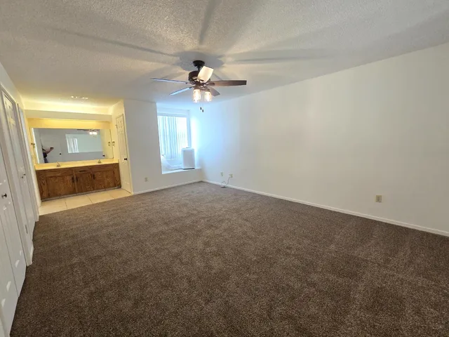 a view of a big room with windows and chandelier fan
