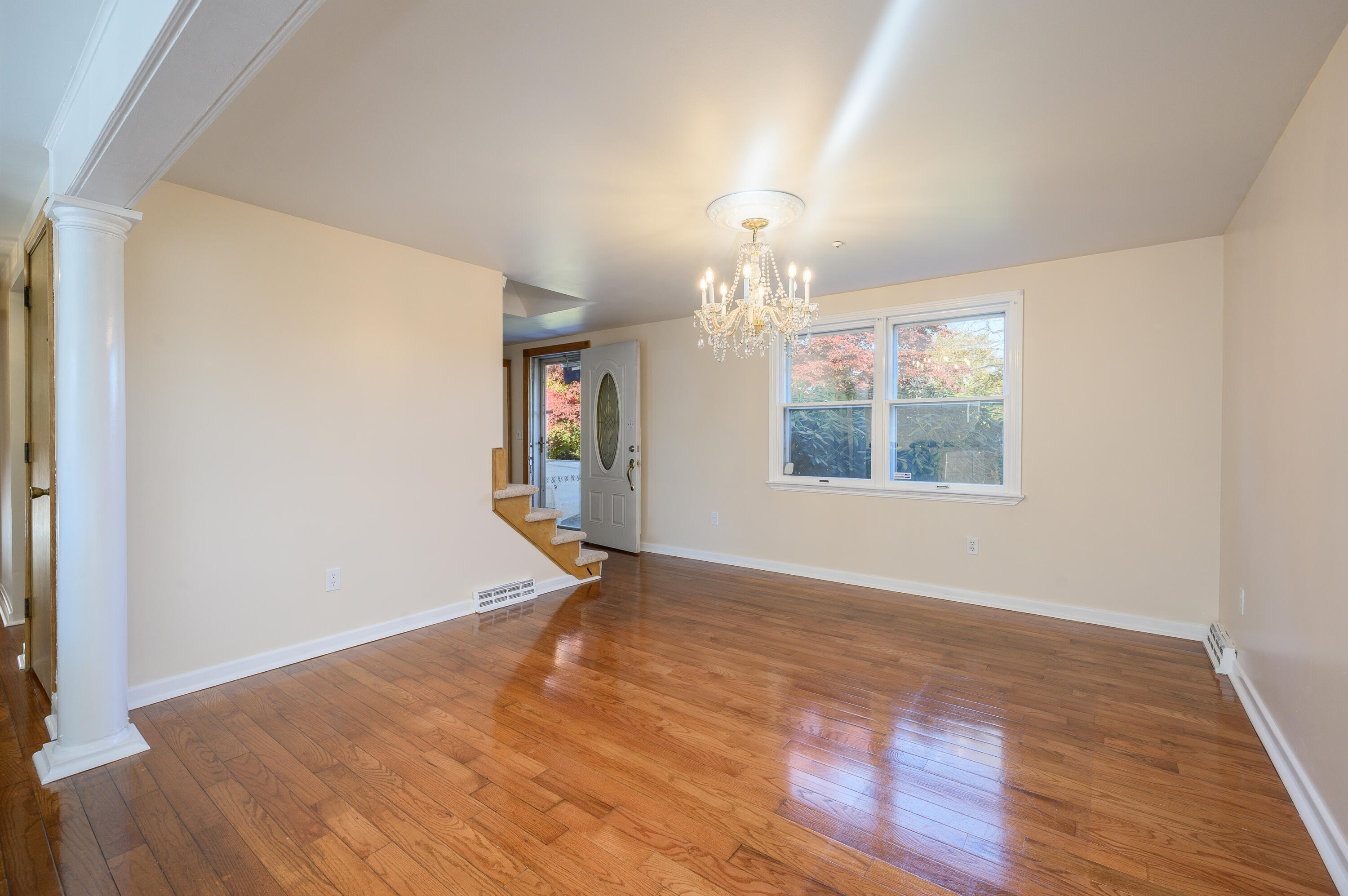 906 Shore Road Pocasset, MA 02559 - Photo 6 of 38 an empty room with wooden floor chandelier and windows