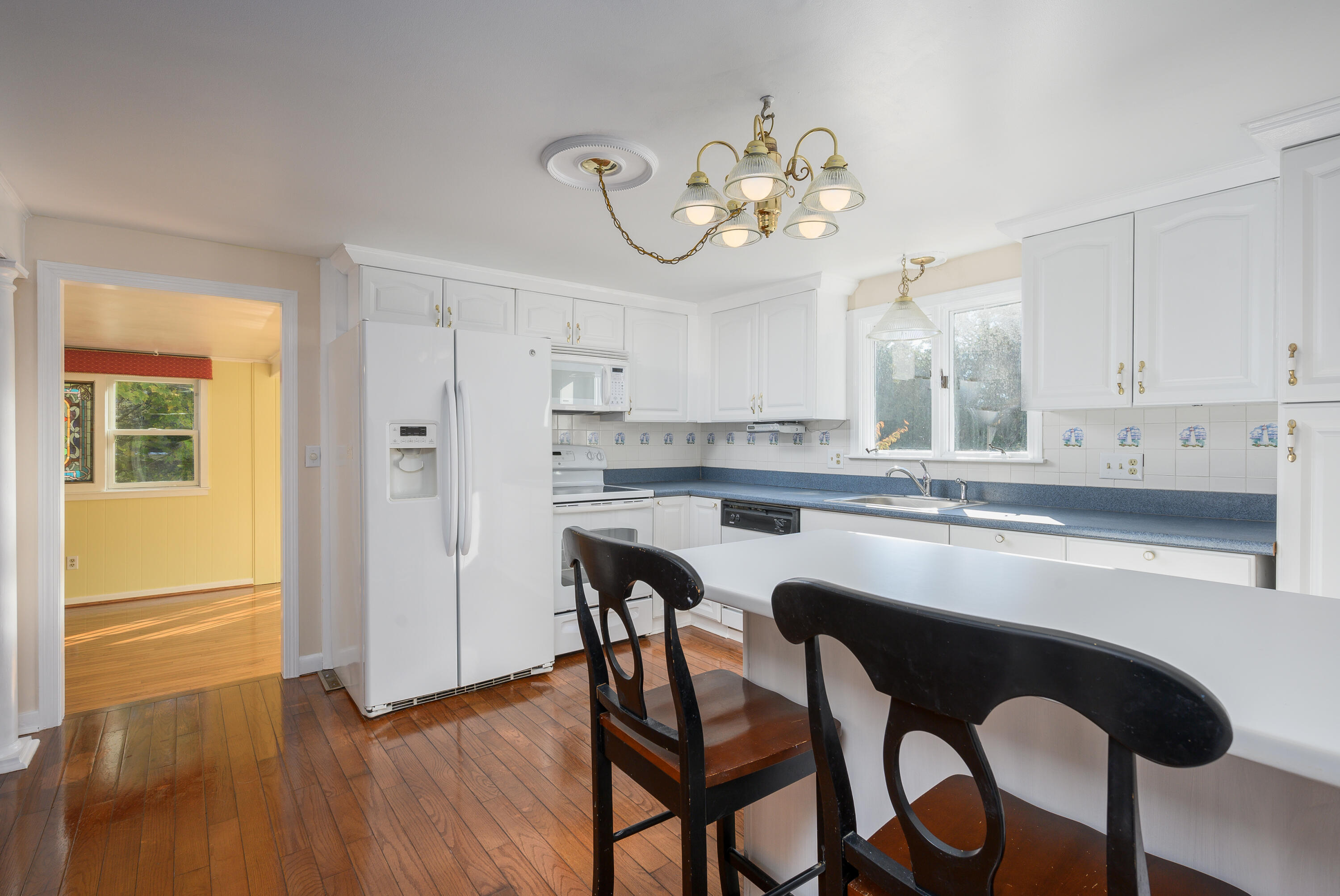 906 Shore Road Pocasset, MA 02559 - Photo 9 of 38 a kitchen with stainless steel appliances granite countertop a table chairs in it and wooden floors