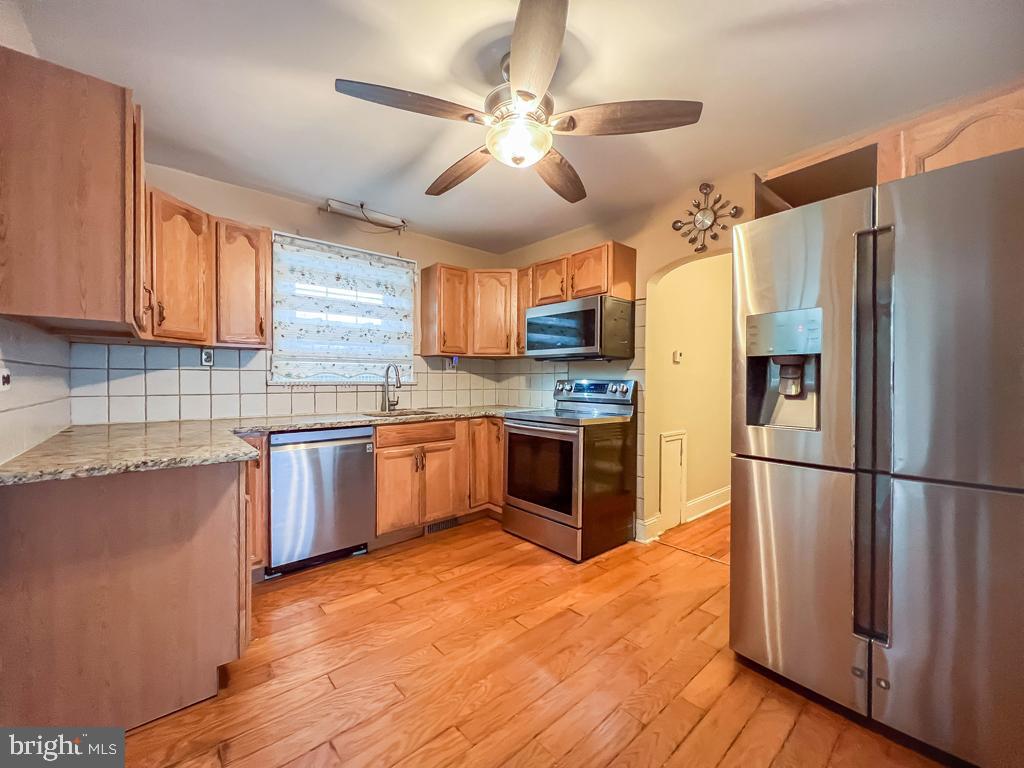 10 Makefield Road Morrisville, PA 19067 - Photo 10 of 46 a kitchen with a refrigerator a stove top oven a sink and dishwasher with wooden floor