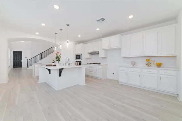 a large white kitchen with kitchen island a sink a center island stainless steel appliances and a cabinets