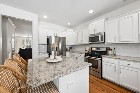 a kitchen with stainless steel appliances granite countertop a kitchen island hardwood floor sink stove microwave and cabinets