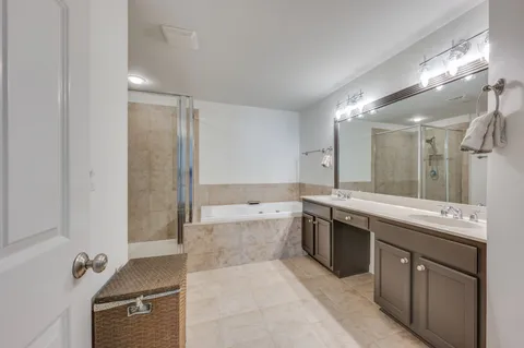 a large bathroom with a granite countertop double vanity sink a mirror and a bathtub