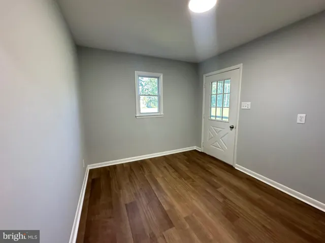 an empty room with wooden floor cabinet and windows