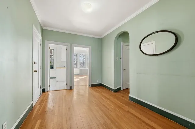 a view of a room with wooden floor mirror and window
