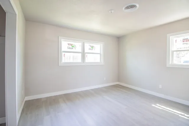 an empty room with wooden floor and windows