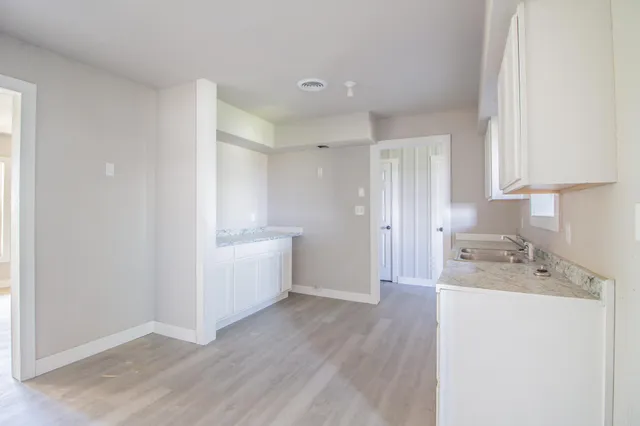 a room view with wooden floor cabinetry and a sink