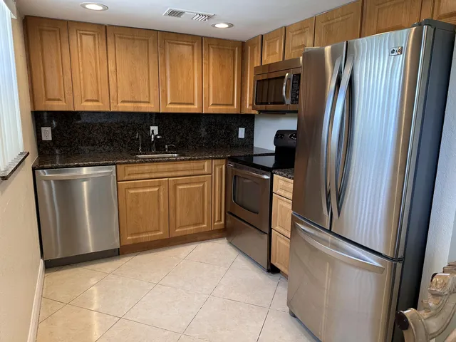 a kitchen with stainless steel appliances granite countertop a refrigerator a stove a sink and dishwasher