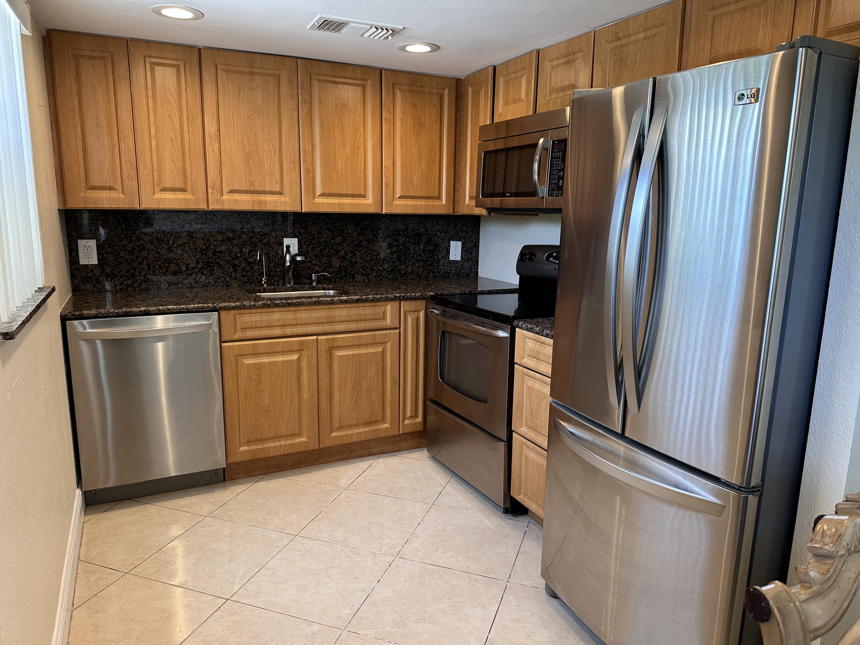 a kitchen with stainless steel appliances granite countertop a refrigerator a stove a sink and dishwasher