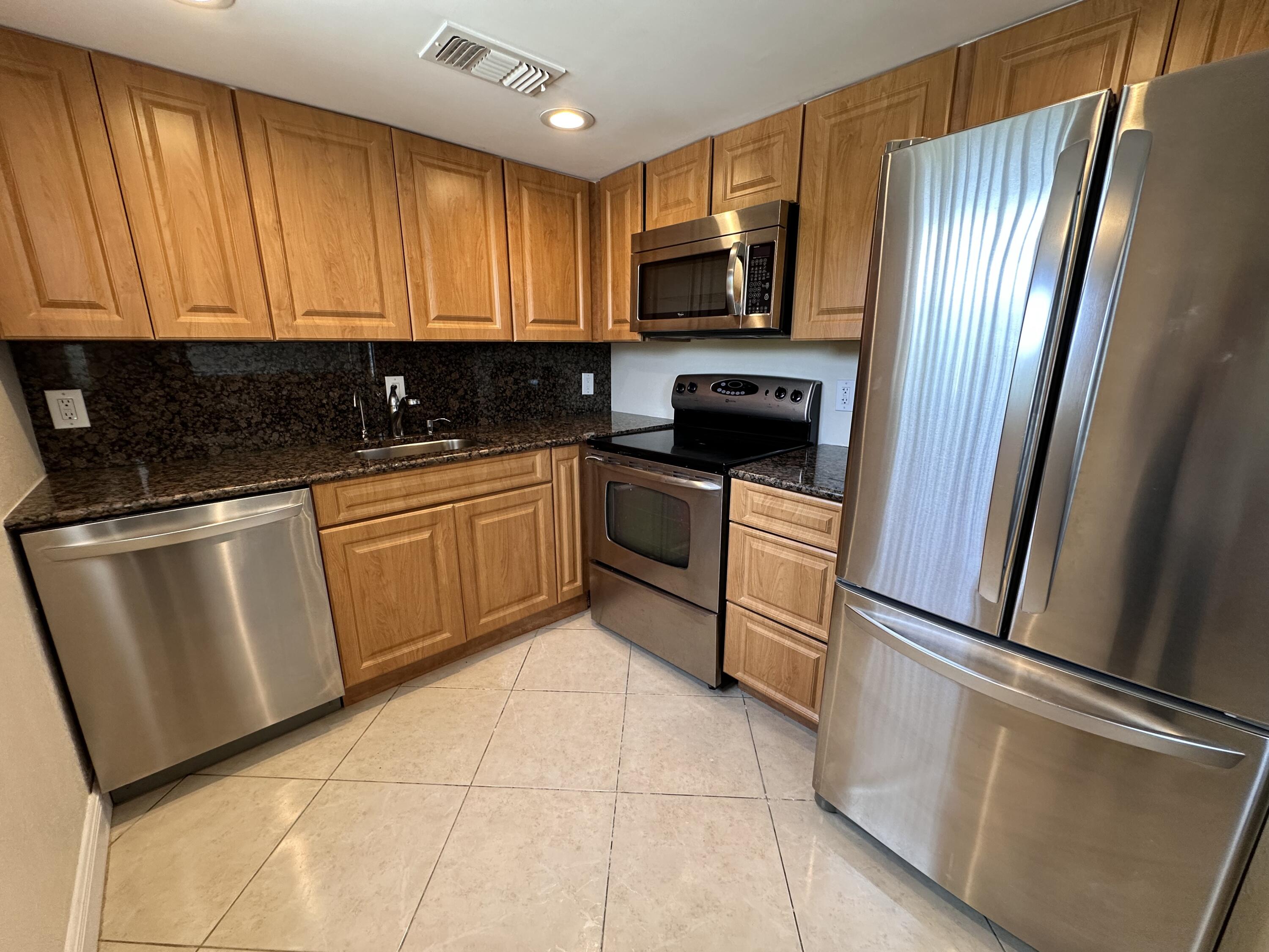 433 Saxony Way Delray Beach, FL 33446 - Photo 14 of 49 a kitchen with granite countertop a refrigerator and a sink