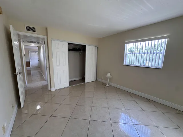 a view of an empty room with closet and a window