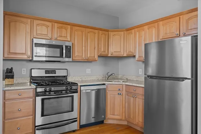 a kitchen with stainless steel appliances granite countertop a refrigerator stove a sink and dishwasher with wooden cabinets