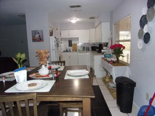 a kitchen with sink refrigerator dining table and chairs