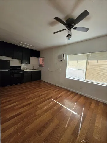 a view of kitchen and empty room with wooden floor