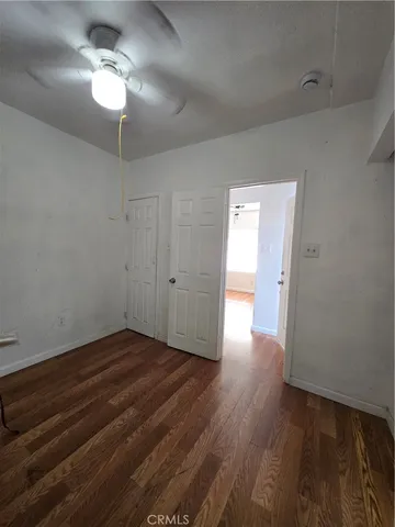 a view of empty room with wooden floor and ceiling fan