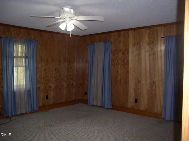 a view of a livingroom with a chandelier fan and windows