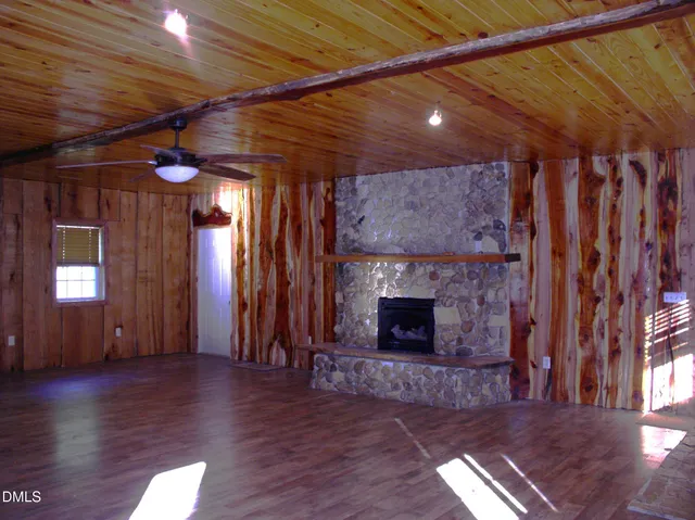 a view of an empty room with wooden floor and a fireplace