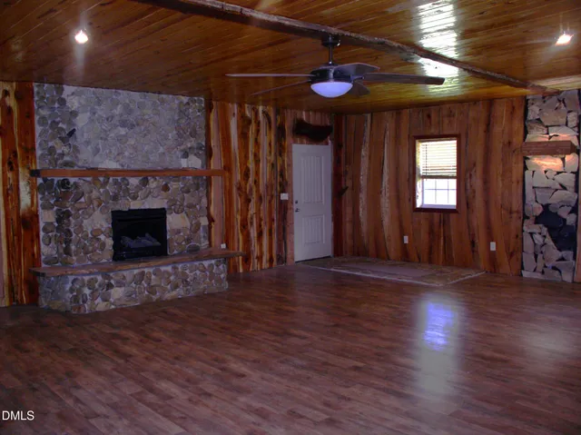 a view of an empty room with wooden floor fireplace and a window