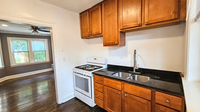 a kitchen with granite countertop stainless steel appliances a sink stove and cabinets