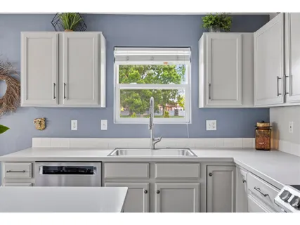a kitchen with stainless steel appliances a sink stove and white cabinets