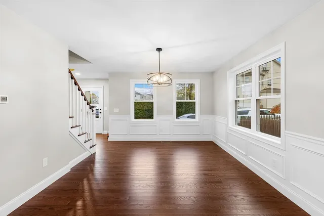 a view of an empty room with wooden floor and window