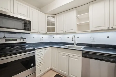 a kitchen with granite countertop white cabinets and stainless steel appliances