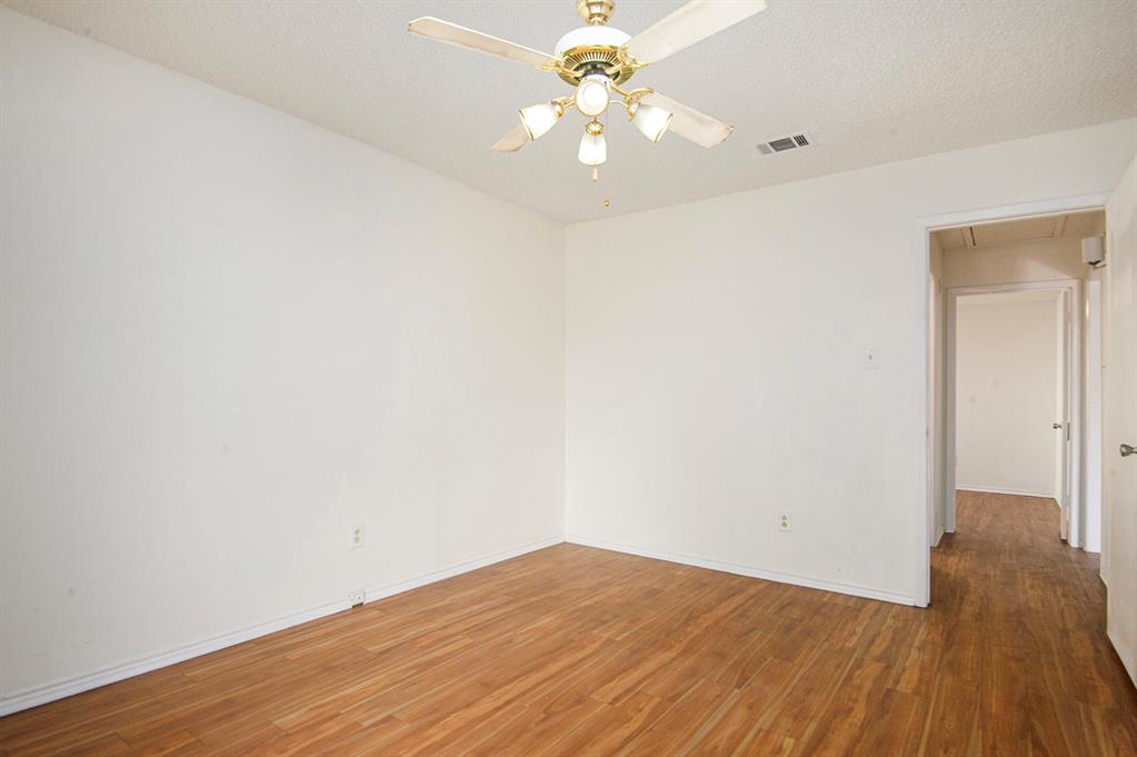 6819 West Cleburne Road Fort Worth, TX 76133 - Photo 16 of 24 an empty room with wooden floor and a ceiling fan