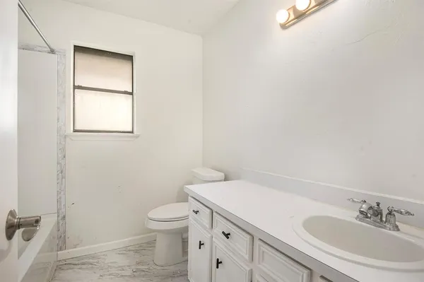 a bathroom with a granite countertop toilet a sink and a mirror