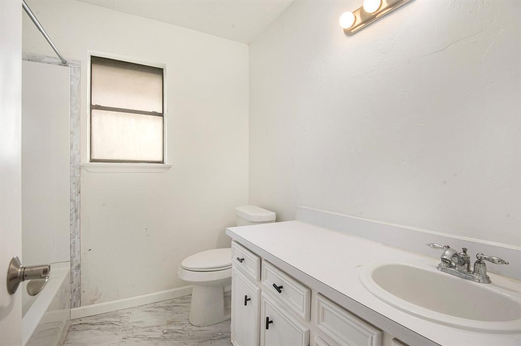 6819 West Cleburne Road Fort Worth, TX 76133 - Photo 17 of 24 a bathroom with a granite countertop toilet a sink and a mirror