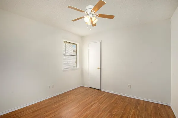 an empty room with wooden floor and a ceiling fan