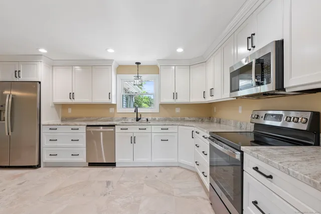 a kitchen with granite countertop white cabinets and stainless steel appliances