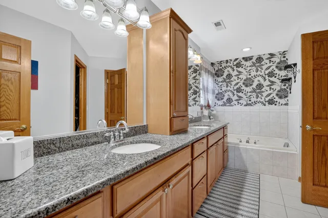 a bathroom with a granite countertop double vanity sink a mirror and a bathtub