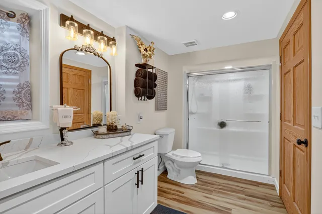 a bathroom with a granite countertop sink toilet a mirror and shower