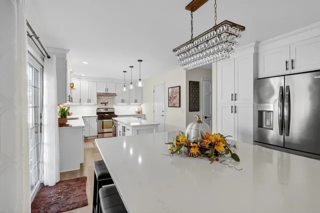 a kitchen with stainless steel appliances refrigerator dining table and chairs
