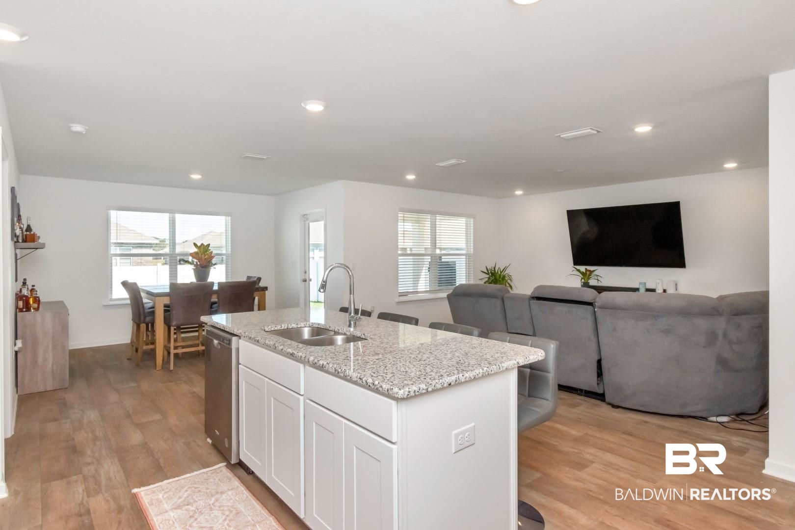 10921 Northern Dancer Court Daphne, AL 36526 - Photo 16 of 32 Kitchen featuring an island with sink, white cabinetry, light wood-type flooring, plenty of natural light, and sink