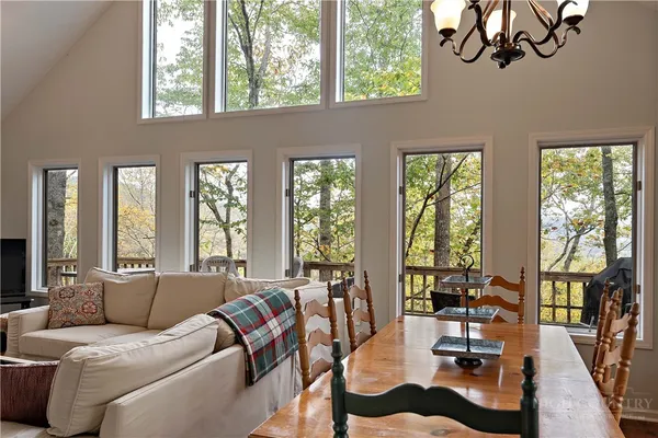 a living room with furniture large windows and wooden floor