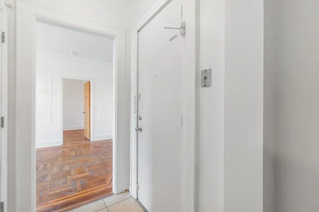 a view of a hallway with wooden floor and a bathroom