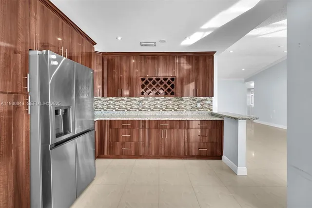 a view of kitchen with stainless steel appliances kitchen island granite countertop a refrigerator and cabinets
