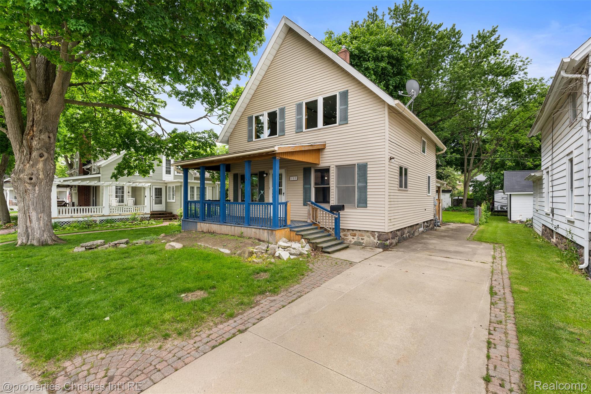 158 South Rawles Street Romeo, MI 48065 - Photo 2 of 53 Two-story residence featuring light-colored horizontal siding, a covered front porch with blue columns and railings, and a stone foundation