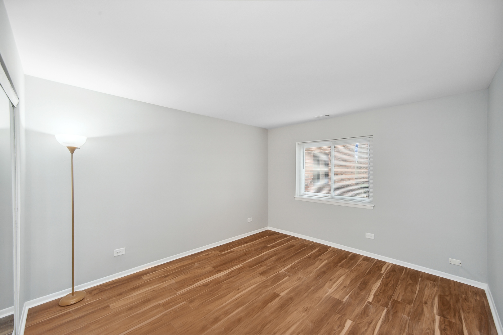 1779 West Algonquin Road, Unit 1A Mount Prospect, IL 60056 - Photo 11 of 15 a view of an empty room with wooden floor and a window