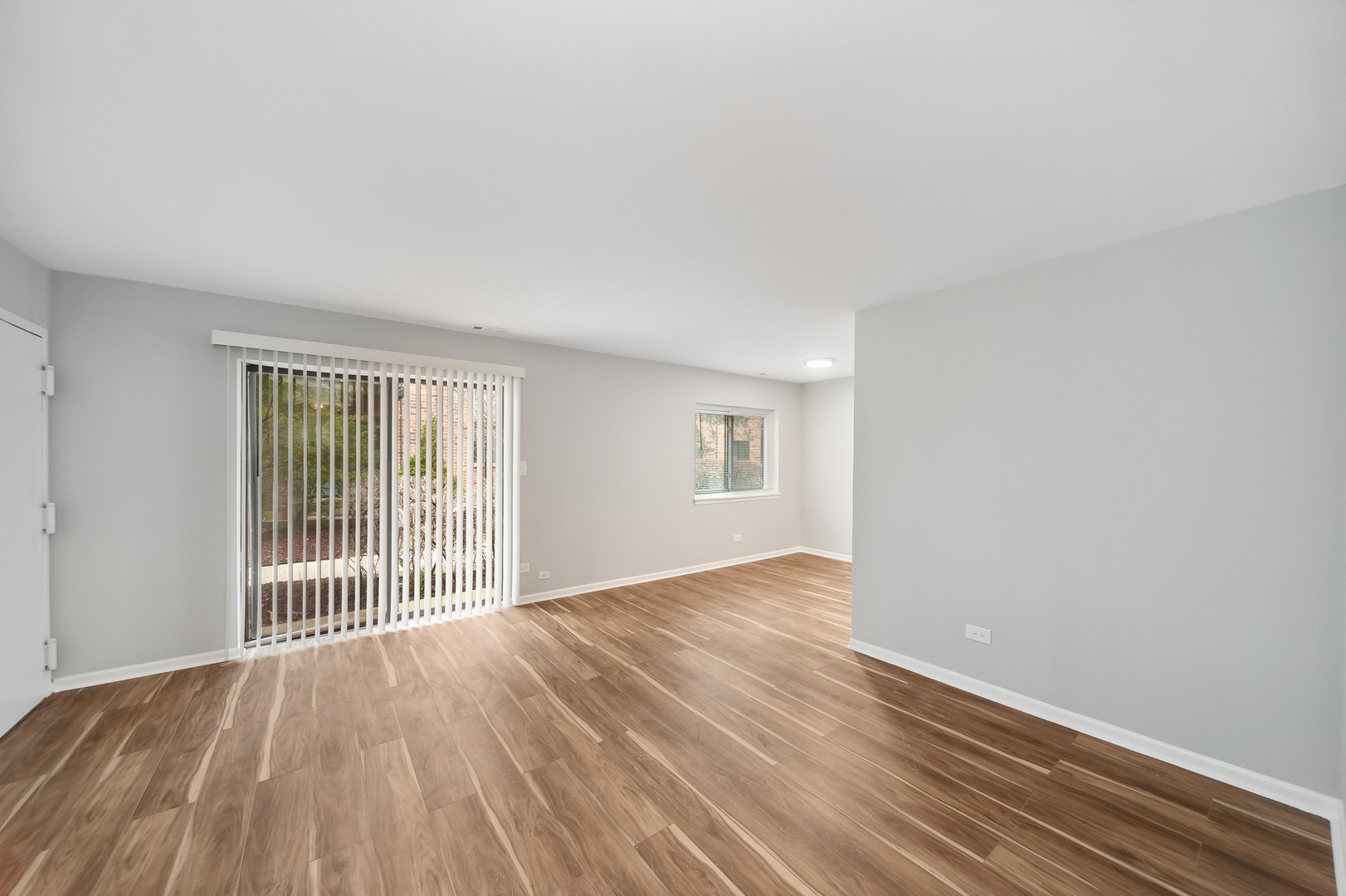 1779 West Algonquin Road, Unit 1A Mount Prospect, IL 60056 - Photo 4 of 15 an empty room with wooden floor and windows