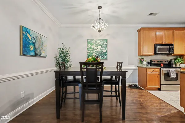 a kitchen with stainless steel appliances granite countertop a refrigerator a stove a dining table and chairs with wooden floor