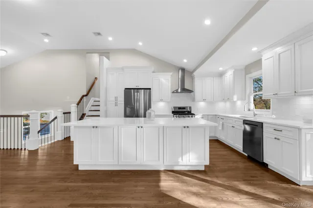 a kitchen with stainless steel appliances granite countertop a white cabinets a sink a stove a dining table and chairs