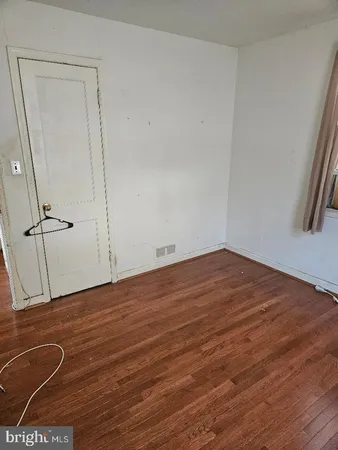 an empty room with wooden floor and a ceiling fan