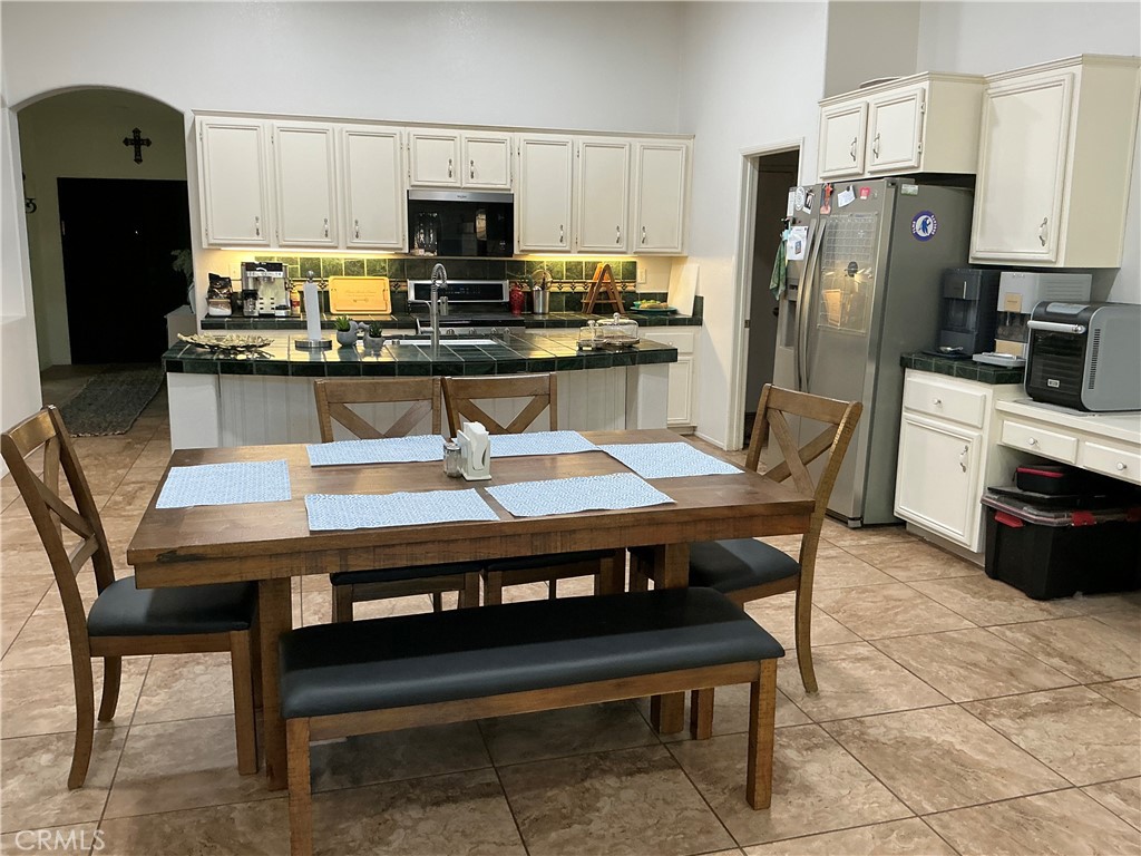 12644 Avocado Way Riverside, CA 92503 - Photo 2 of 6 a kitchen with stainless steel appliances a table chairs microwave and refrigerator