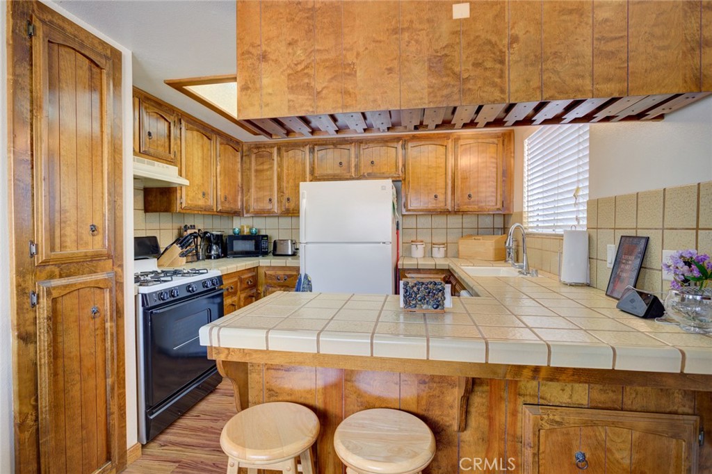 1165 Maple Street, Unit E Arroyo Grande, CA 93420 - Photo 16 of 50 a kitchen with a refrigerator a stove a sink dishwasher and wooden cabinets with wooden floor