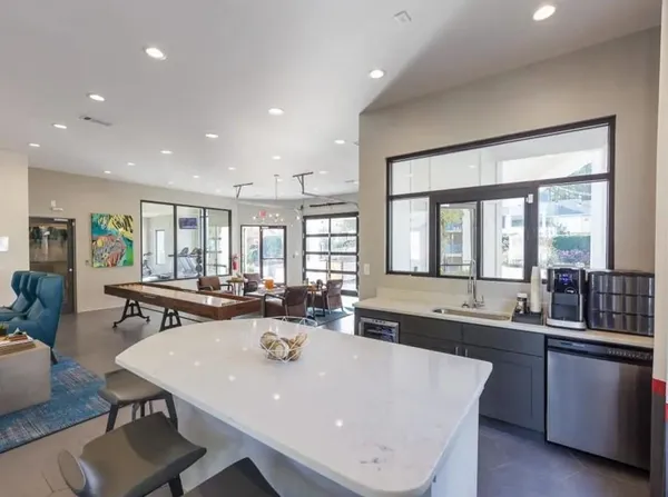 a large dining hall with stainless steel appliances a sink and a large window
