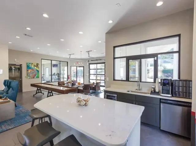 a large dining hall with stainless steel appliances a sink and a large window